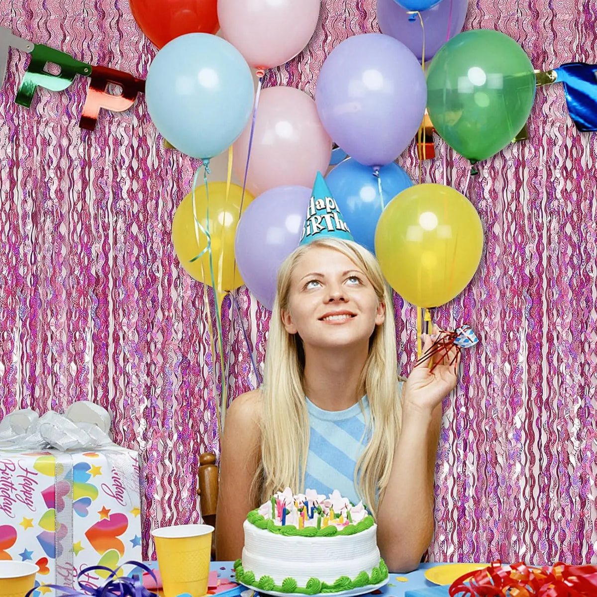 Eine junge Frau lächelt und hält einen Ballonstrauß vor einem pinken Tinsel-Hintergrund für eine Veranstaltung.