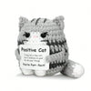 A handmade gray and white crochet mini cat plush with a sign that reads You're Purr-fect