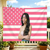 A woman wearing patriotic face paint stands in front of a large American flag tapestry.