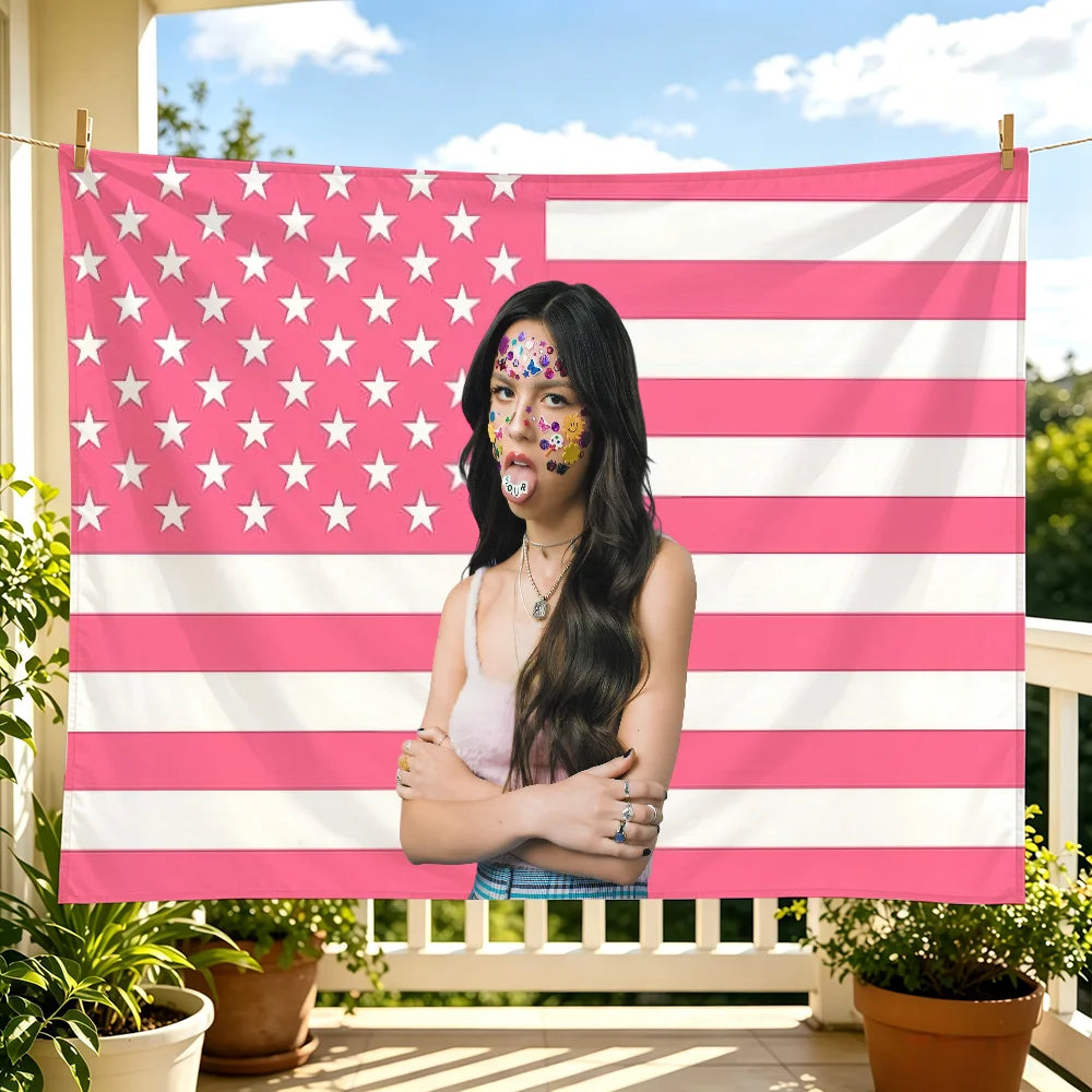 A woman wearing patriotic face paint stands in front of a large American flag tapestry.