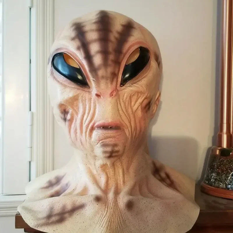 A realistic cute alien full-face latex mask with large black eyes and textured skin details.