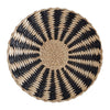 Round woven straw wall decor hanging with black and beige geometric patterns