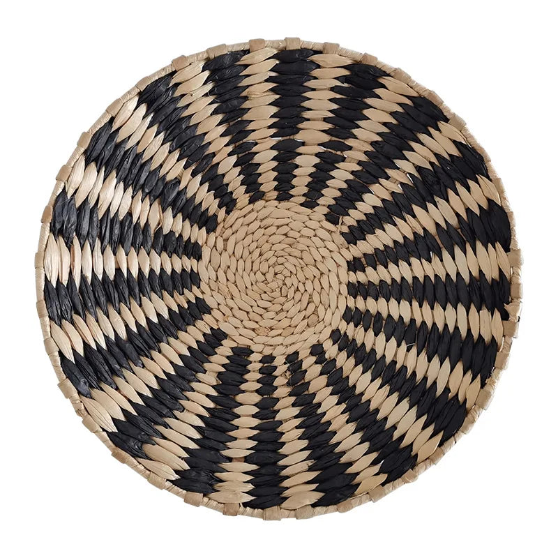 Round woven straw wall decor hanging with black and beige geometric patterns