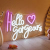An illuminated neon sign spelling out Hello Gorgeous on a textured wall.