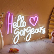 An illuminated neon sign spelling out Hello Gorgeous on a textured wall.