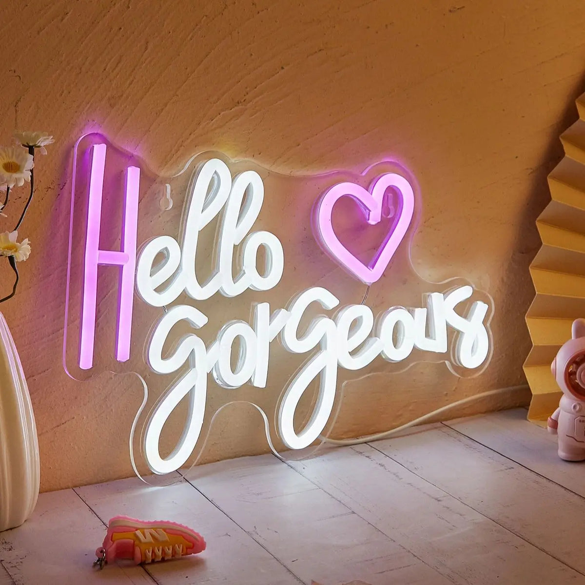 An illuminated neon sign spelling out Hello Gorgeous on a textured wall.