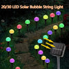 A string of 20/30 LED solar bubble lights illuminating a garden path at night.