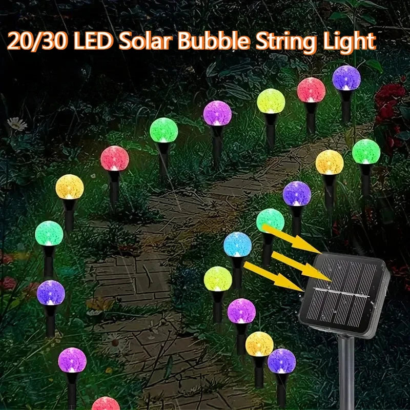 A string of 20/30 LED solar bubble lights illuminating a garden path at night.