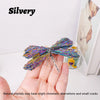 A hand holds a silvery crystal dragonfly figurine with iridescent colors against a white background.