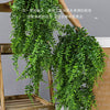 Une plante artificielle verte luxuriante avec de longues feuilles retombantes, suspendue sur un support en bois.