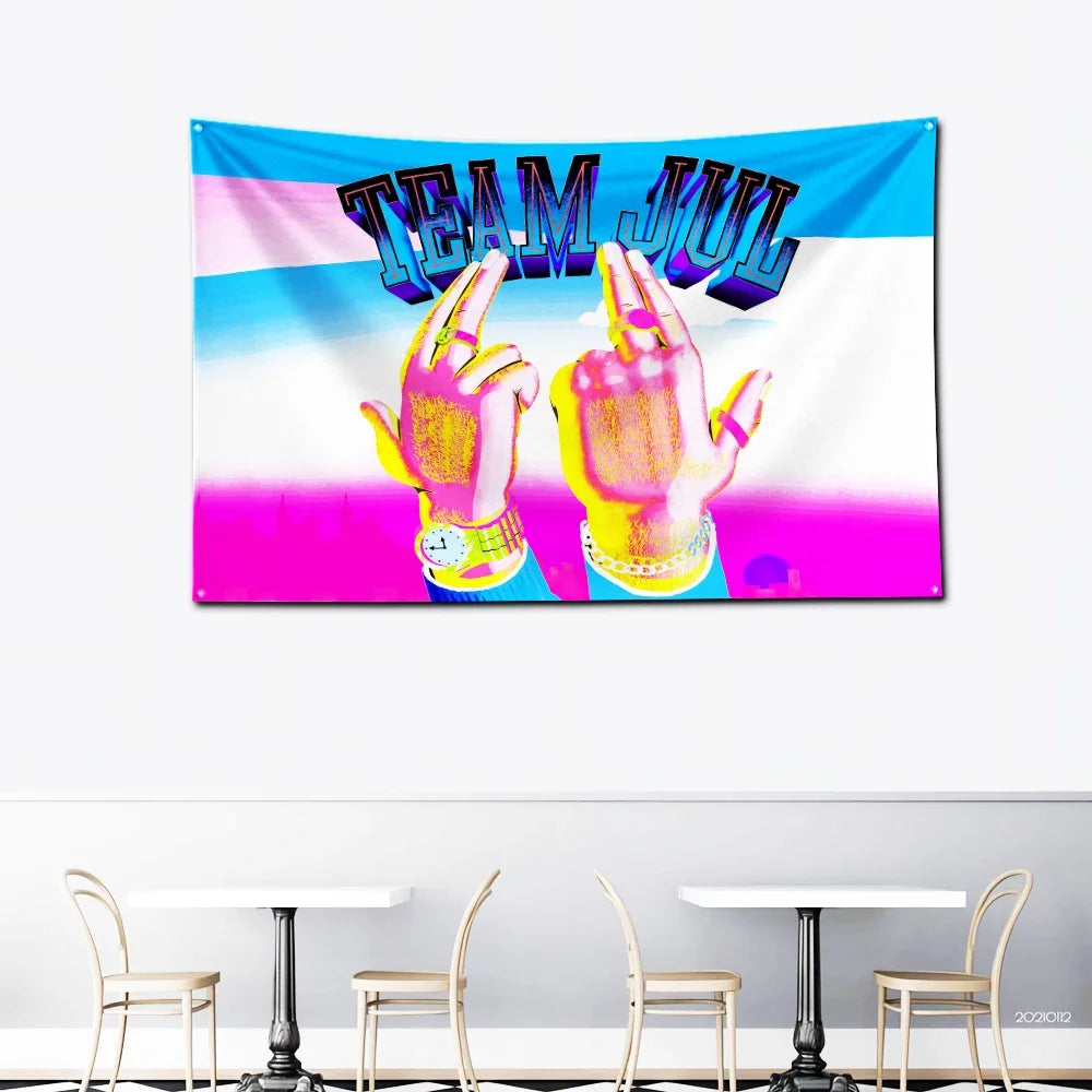 A vibrant pink and blue banner featuring the text TEAM JUL in large, stylized letters with two hands making a peace sign.