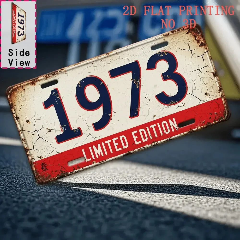 A distressed vintage metal tin sign with the number 1973 is shown in a side view on a dark surface.