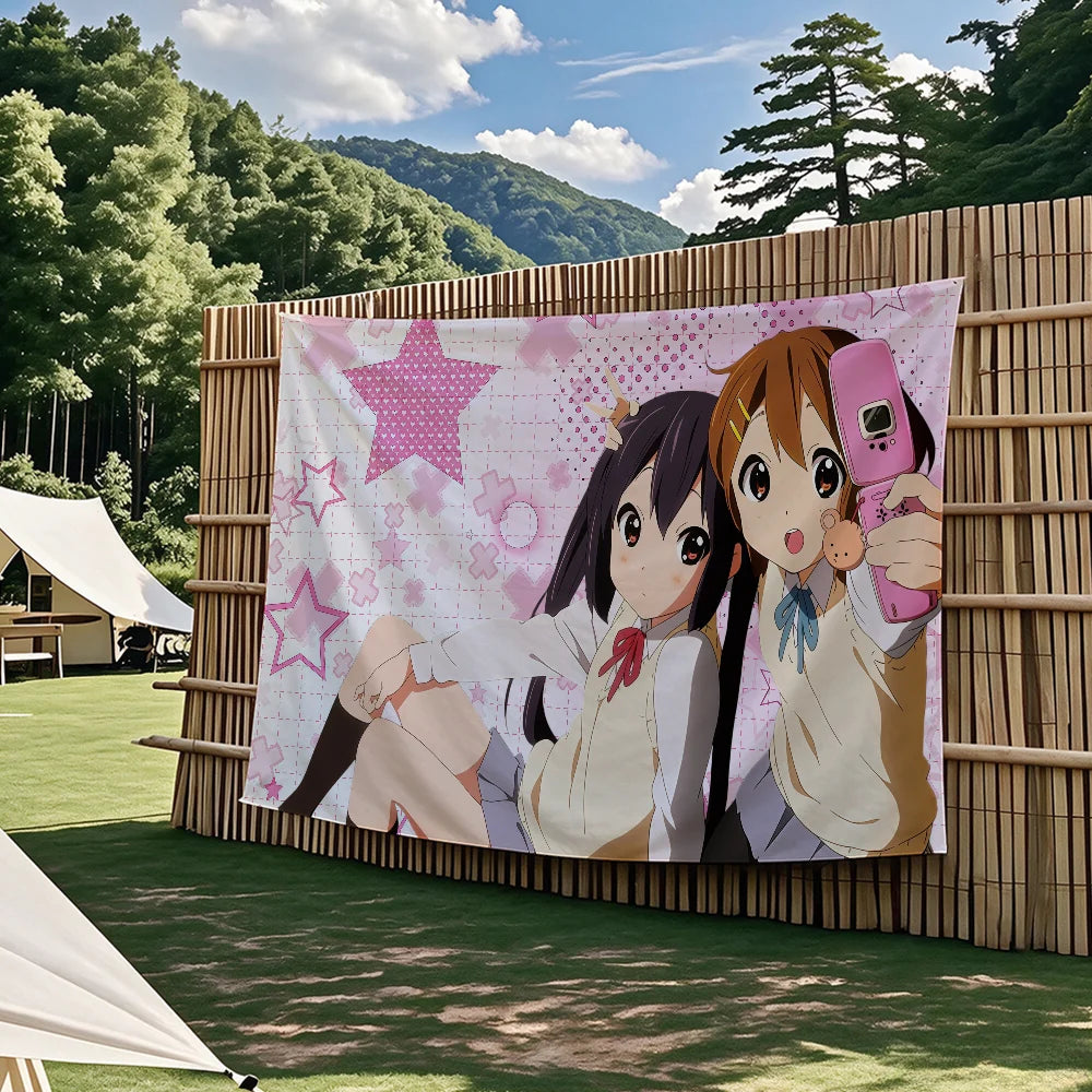 A large tapestry featuring two anime characters from K-On! in a pink floral pattern displayed outdoors.