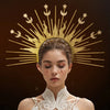 A woman wearing a celestial halo headband with gold and silver star accents against a dark background.