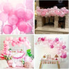 A display of pink and white balloons arranged in an arch shape for events.
