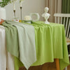A lime green rectangular tablecloth is draped with a pale green napkin and set for dining or events.