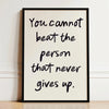 A framed black and white motivational quote print on a light background featuring the text You cannot beat the person that ne