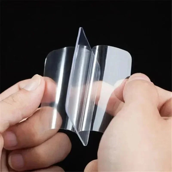 A hand is holding a clear double-sided adhesive tape, showing its transparent and flexible nature.