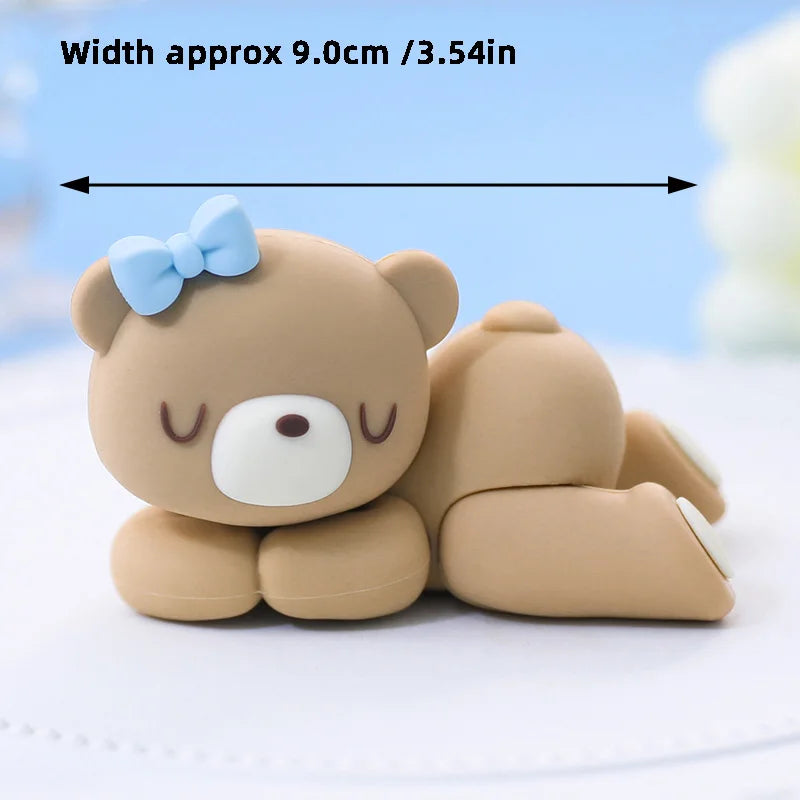 A cute, light brown cartoon elephant cake topper with a blue bow, shown lying on a white surface.