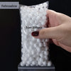 A hand holds a clear plastic bag filled with white polystyrene foam balls for crafting and decorating.