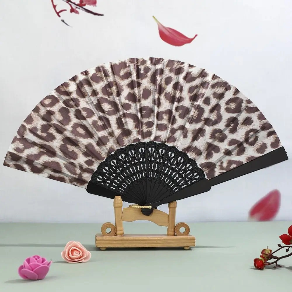 A leopard print folding hand fan with a black handle displayed against a white background.