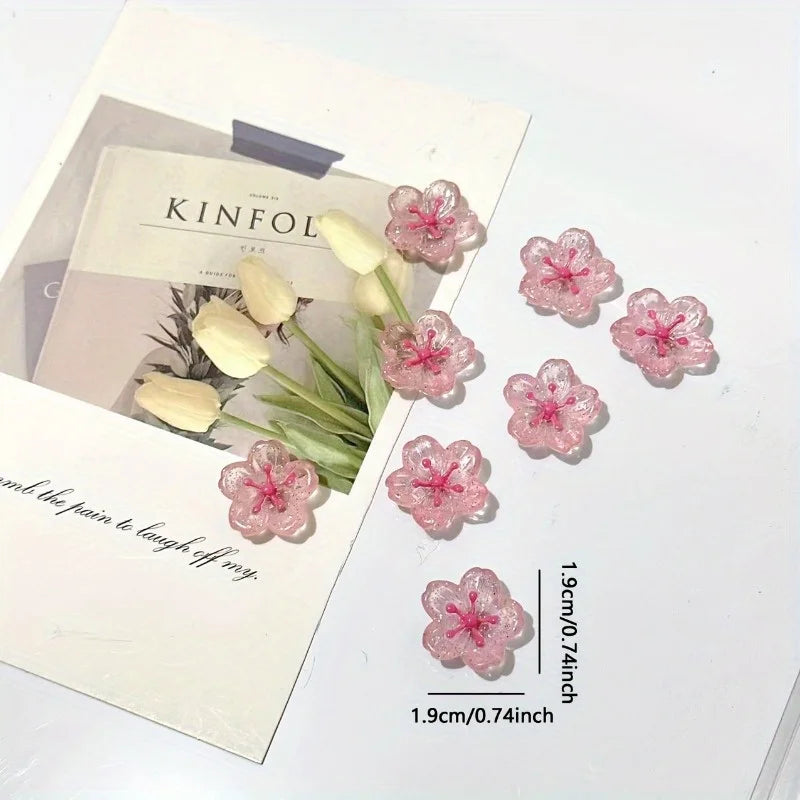 Pink cherry blossom fridge magnets with white petals displayed on a light background.
