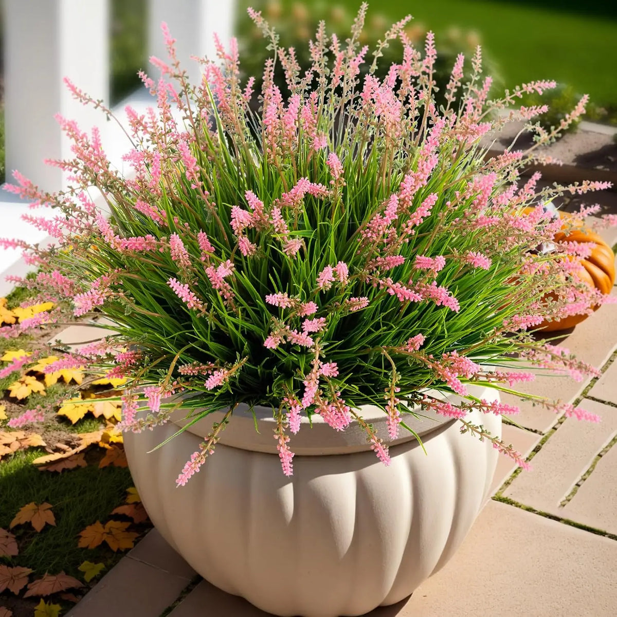 A potted artificial lavender plant with pink flowers in a white ceramic pot