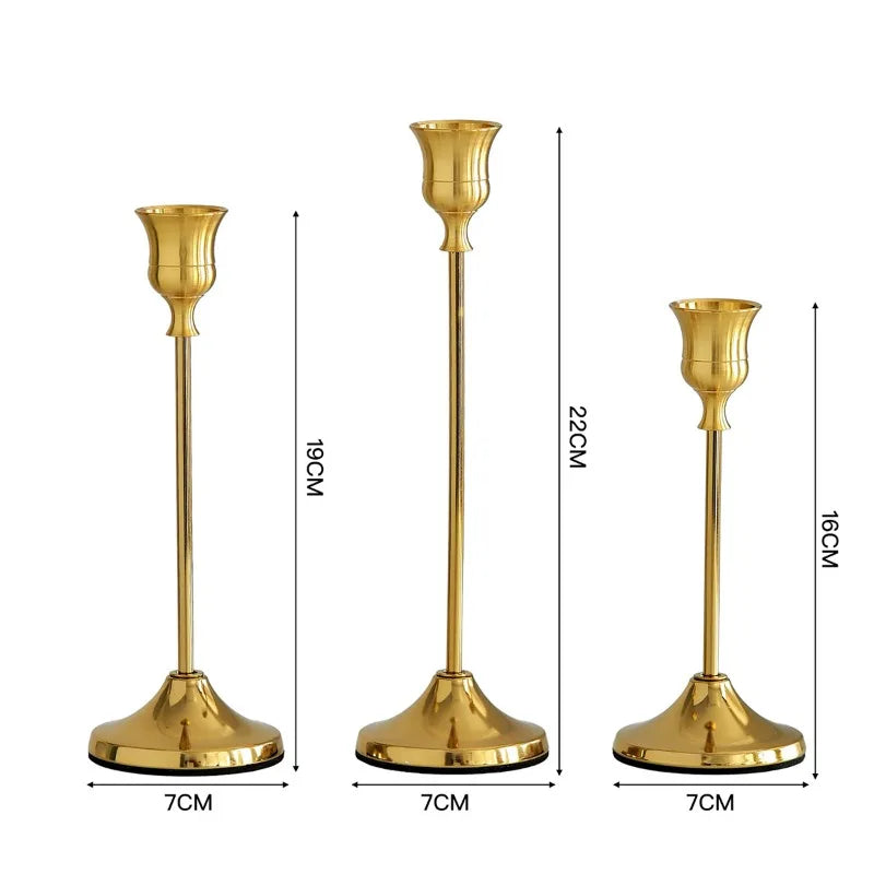 Set of three elegant gold metal candlesticks with flared bases and slender stems.