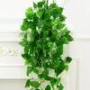 Artificial pothos hanging vines with green leaves decorating a white fireplace mantel