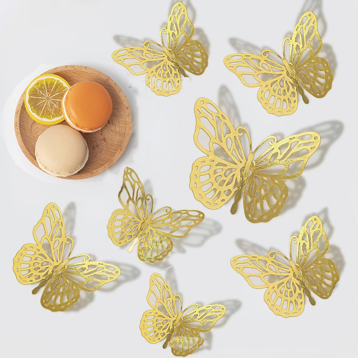 A set of nine gold butterfly wall decor cutouts displayed on a white background with citrus fruit.