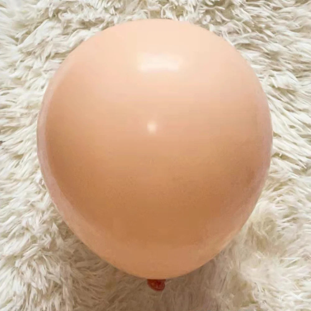 A single, round, pale peach latex balloon resting on a white, fluffy surface.