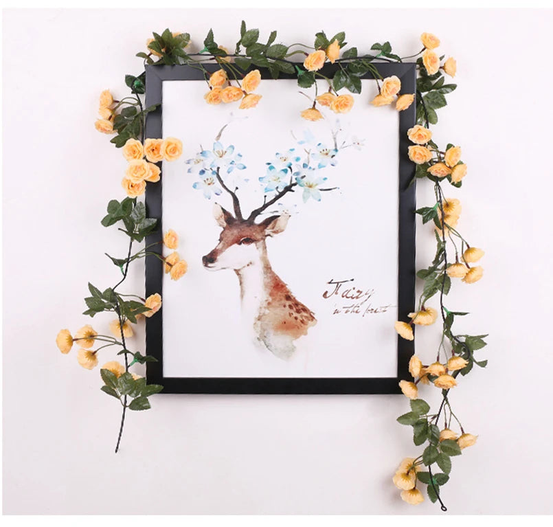 A framed watercolor painting of a deer with blue blossoms surrounded by a silk rose vine garland.