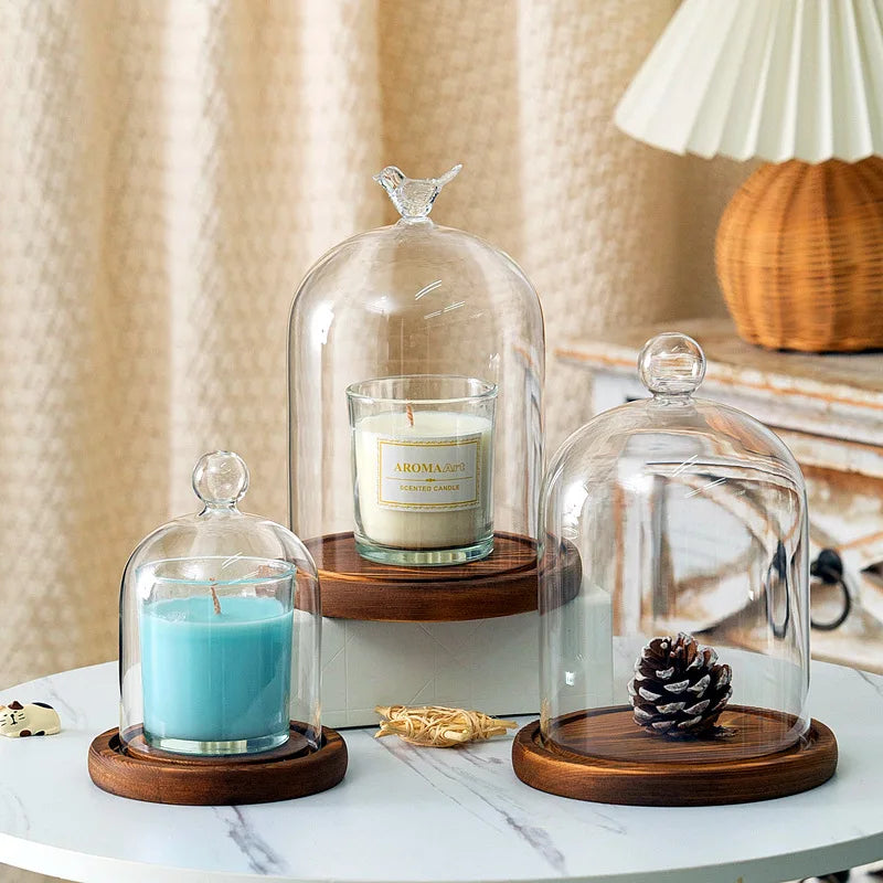 A glass aromatherapy candle holder with a teal candle on a wooden base and dust-proof cover.