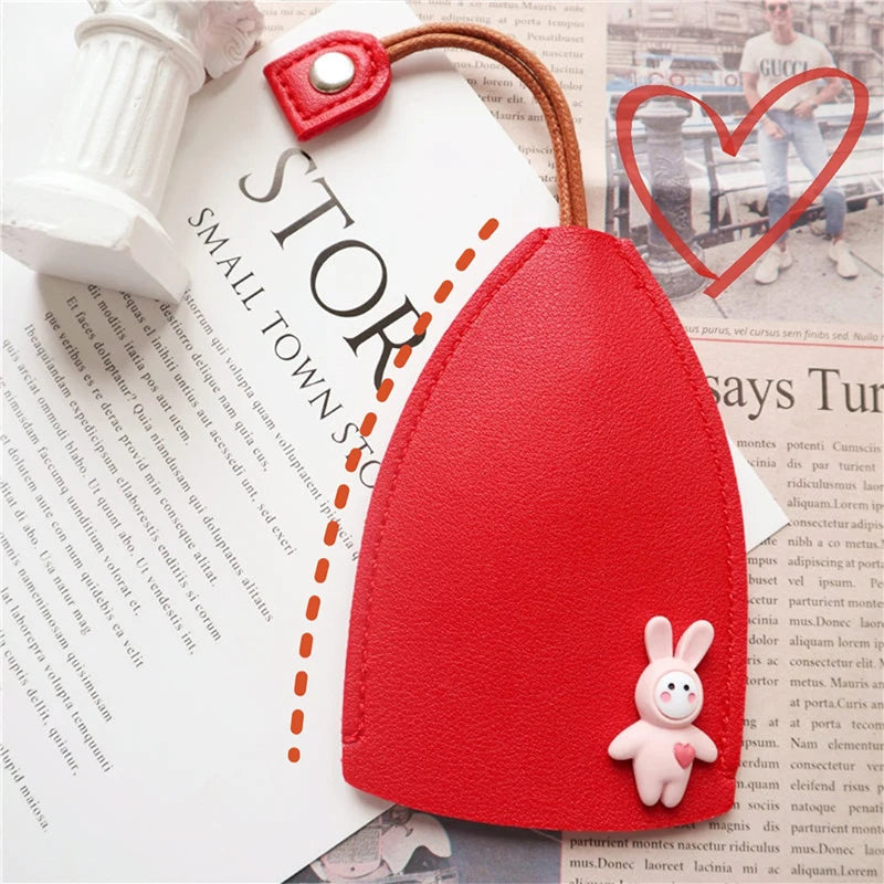 A red cartoon PU leather key holder with a rabbit charm attached, shown against a piece of paper.