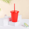 A red plastic cold cup with a lid and straw is displayed on a white surface.
