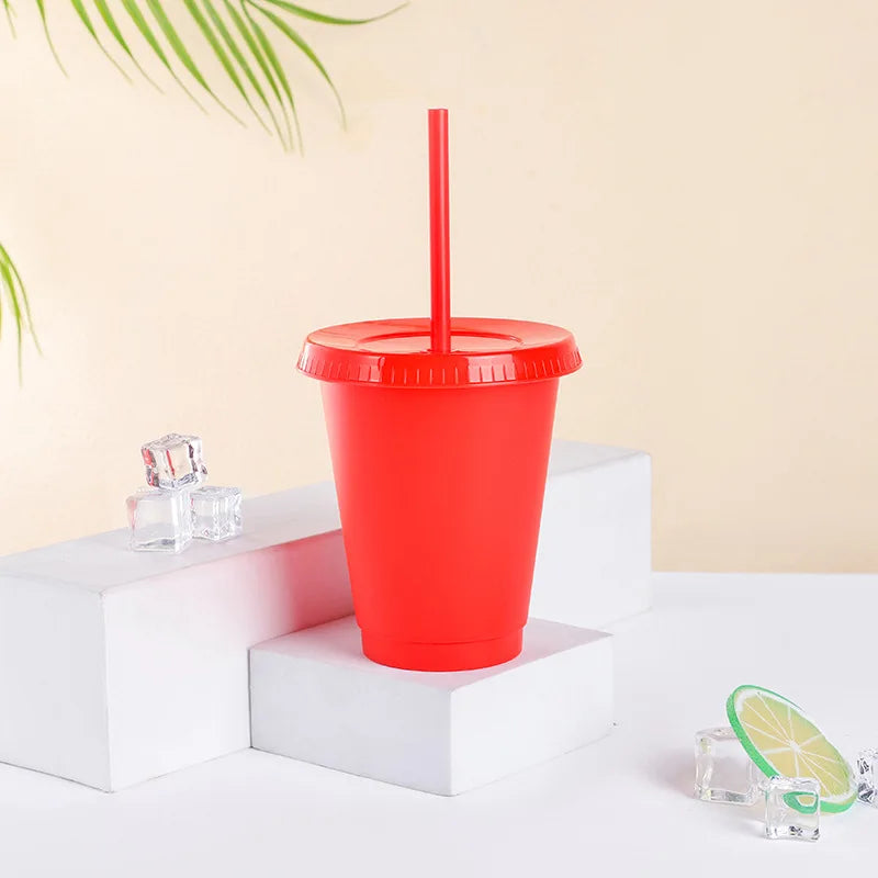 A red plastic cold cup with a lid and straw is displayed on a white surface.