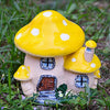 A yellow resin mushroom house garden statue with a small wooden door and windows, set in green grass.