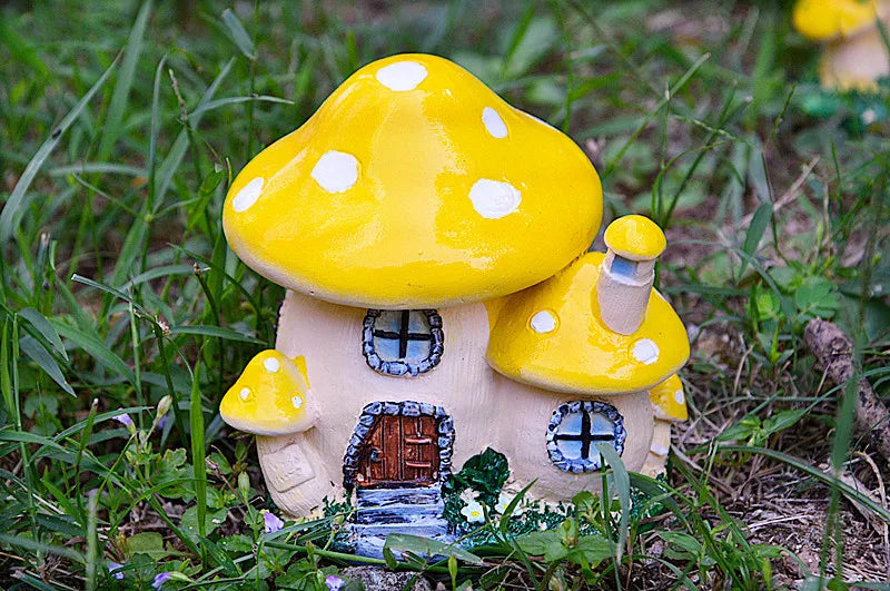 A yellow resin mushroom house garden statue with a small wooden door and windows, set in green grass.