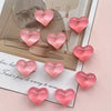 A set of ten heart-shaped pink resin refrigerator magnets arranged on a light background.