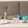 Hand carved wood knot decor resting on a white tray next to a teal mug in a modern living room setting.