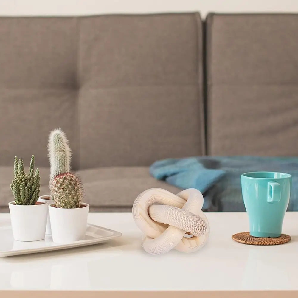 Hand carved wood knot decor resting on a white tray next to a teal mug in a modern living room setting.