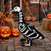 A black and white skeleton goose lawn decor statue placed on a brick path surrounded by autumn foliage and pumpkins.