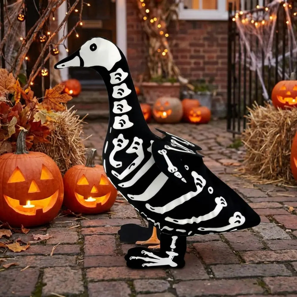 A black and white skeleton goose lawn decor statue placed on a brick path surrounded by autumn foliage and pumpkins.