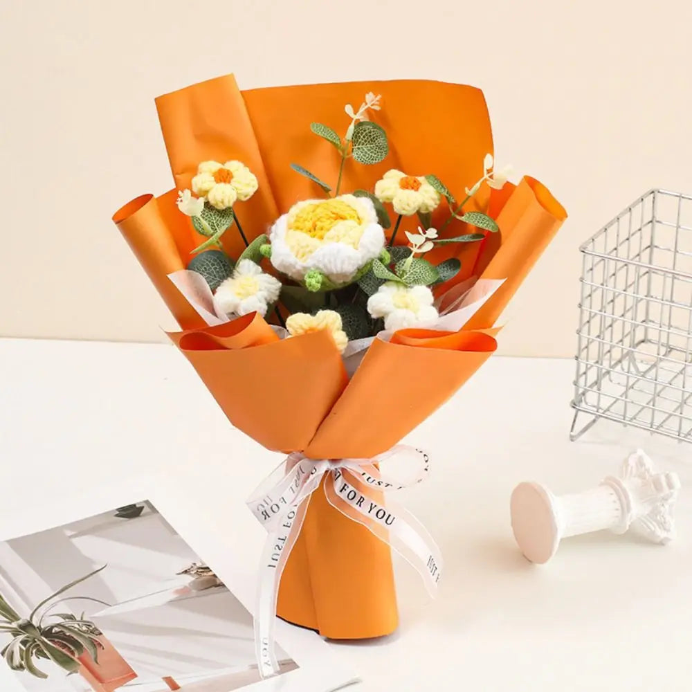 An orange handmade crochet rose flower bouquet with white and yellow blooms tied with a white ribbon.