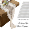 White lace table runner with delicate embroidery and sheer fabric draped over a wooden surface.