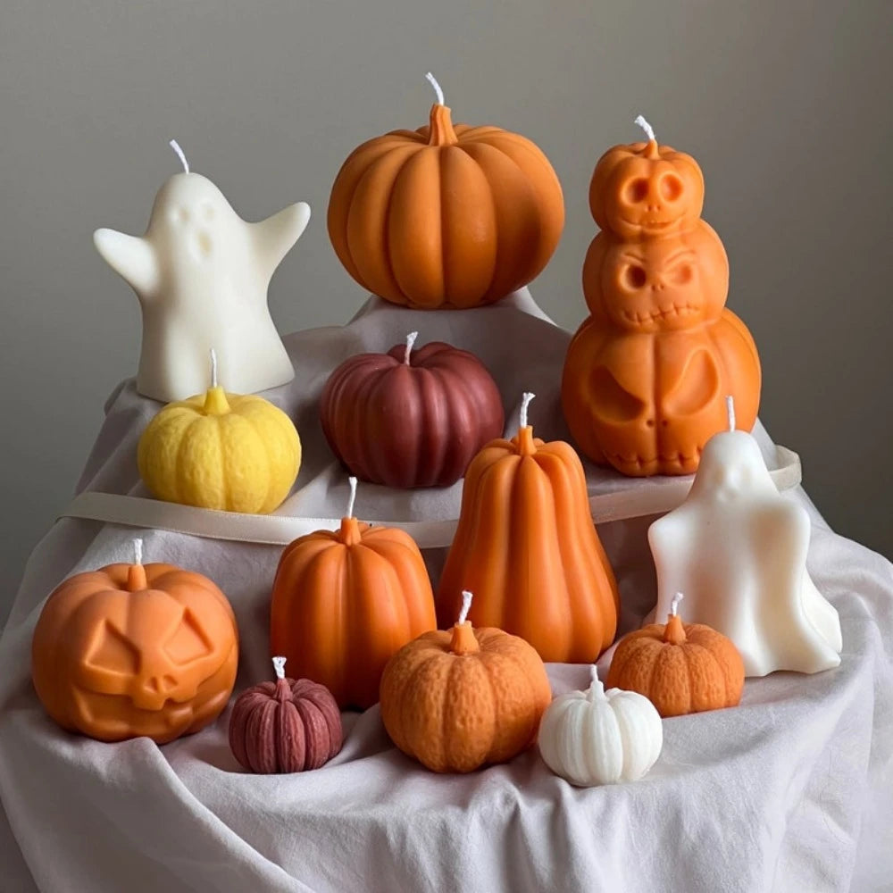 A collection of orange and white pumpkin silicone candle molds arranged on a white cloth.
