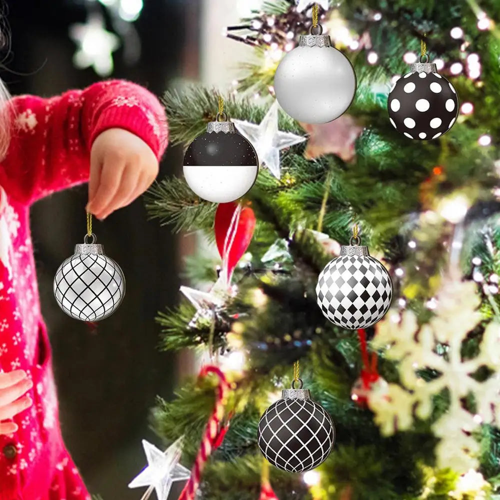 A person hangs various spherical ornaments, including white, black and white polka dot, and silver ones, on a decorated Chris