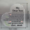 A clear heart-shaped acrylic keepsake plaque engraved with a message for a son, 'I love you now & forever, love, mom'.