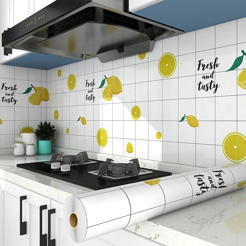 A kitchen wall featuring yellow citrus fruit decals and a black range hood above a countertop.