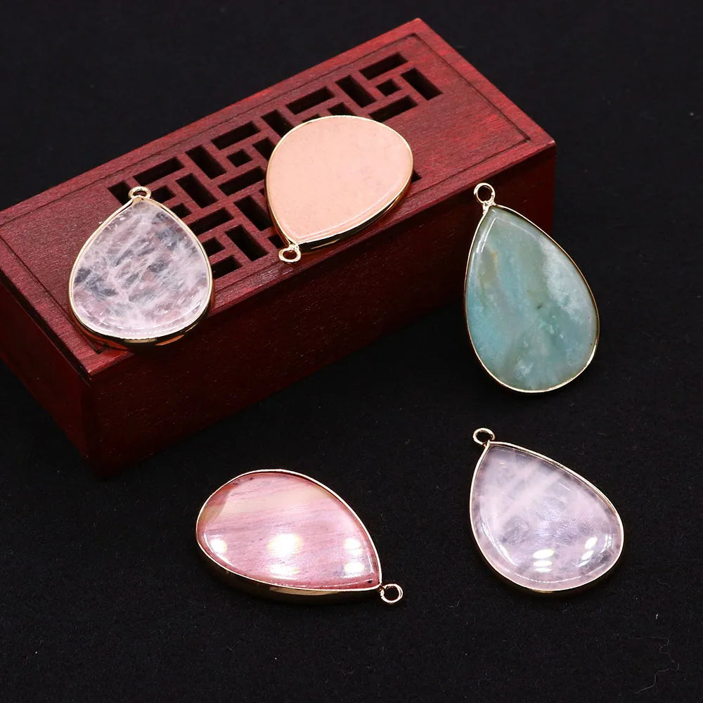 A set of natural agate and rose quartz pendant charms displayed in a wooden box.